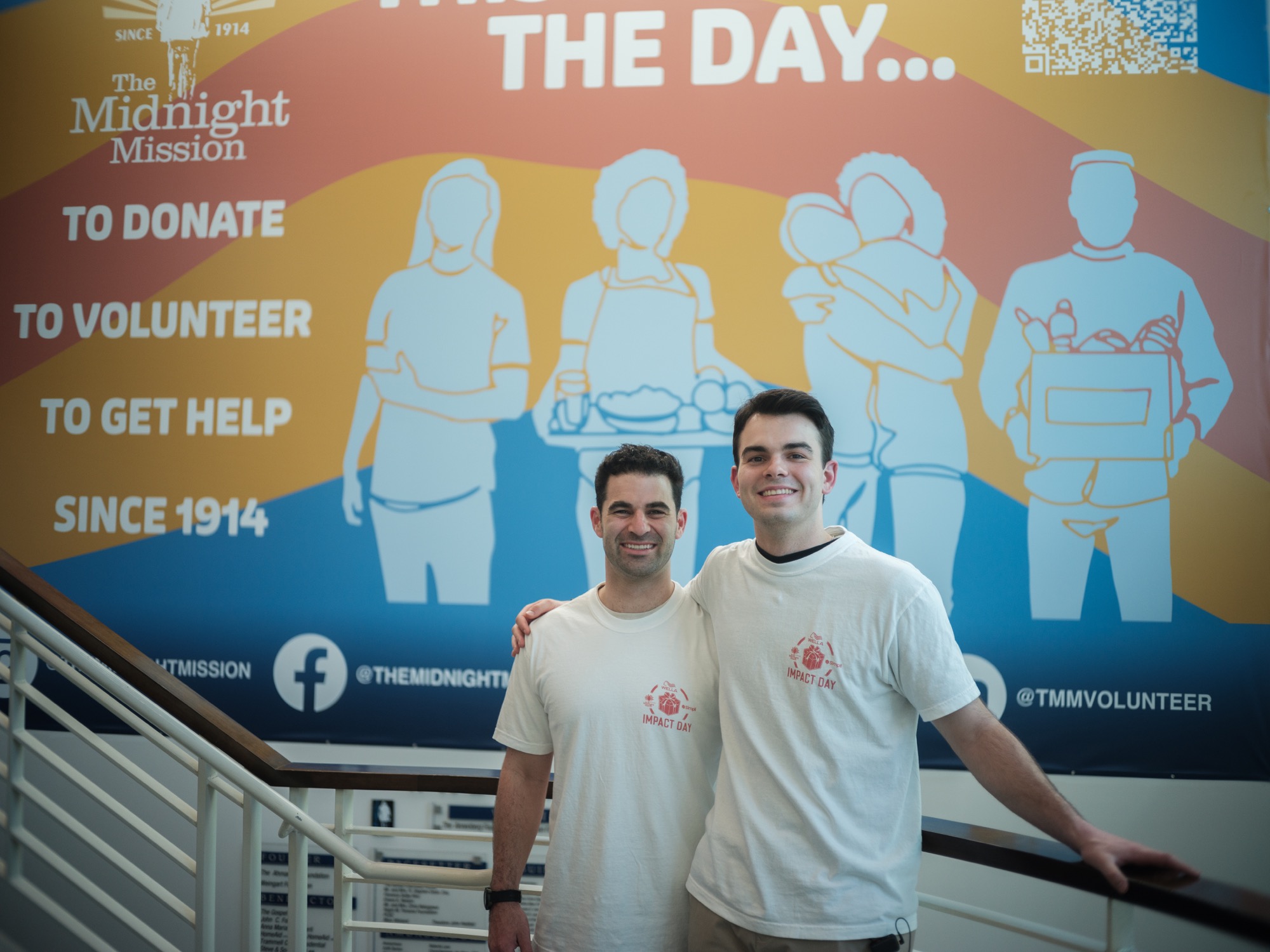 Teddy and Nick in Impact Day t-shirts in front of the Midnight Mission mural