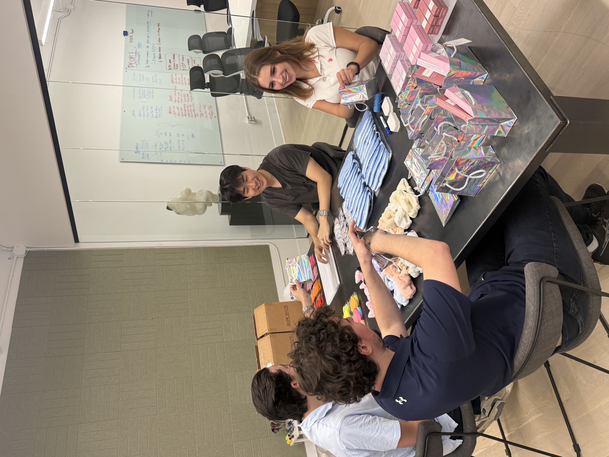 Simpli fellows around an office table packing donation gift bags